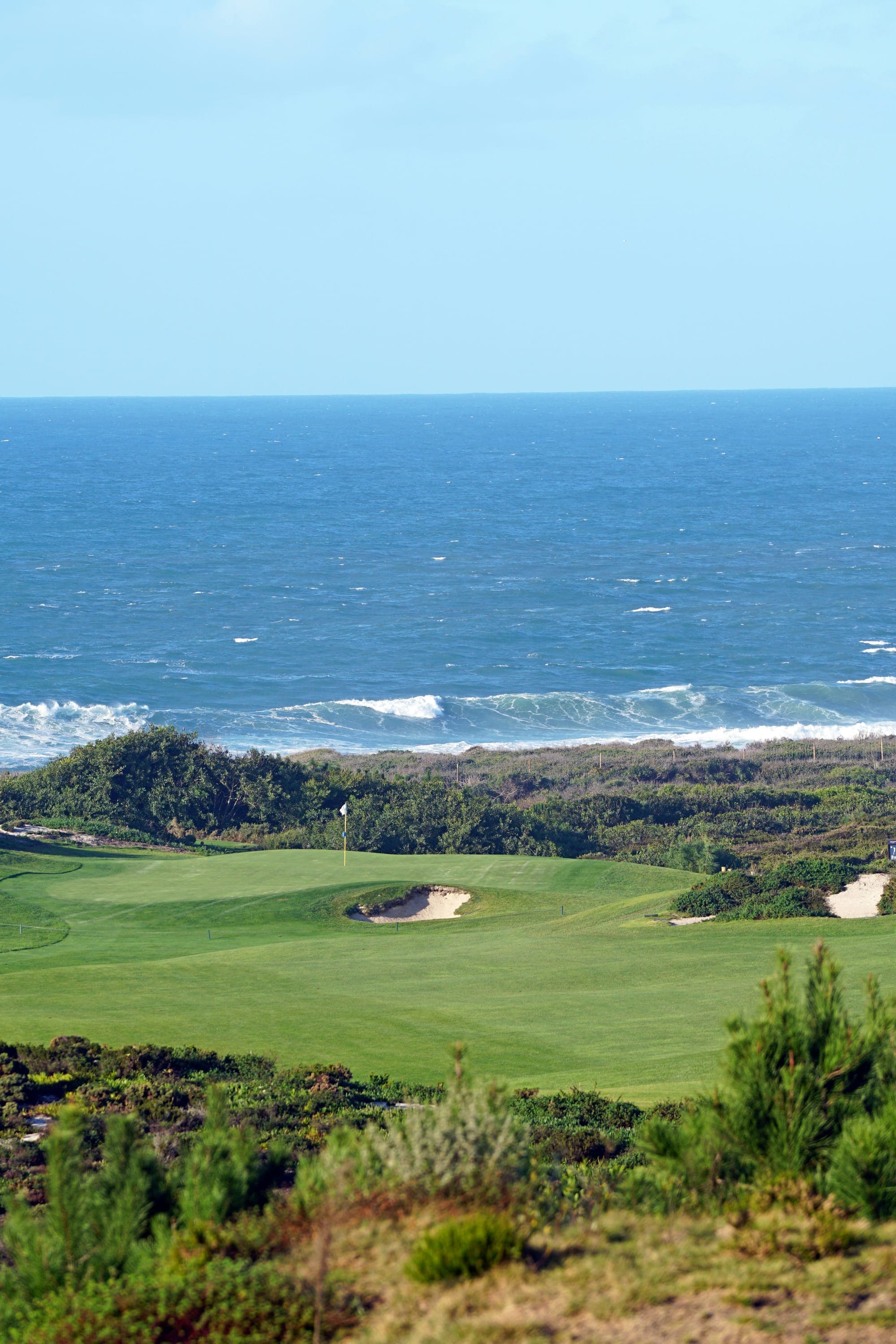 Golf course fairway with ocean view in the background under a clear blue sky