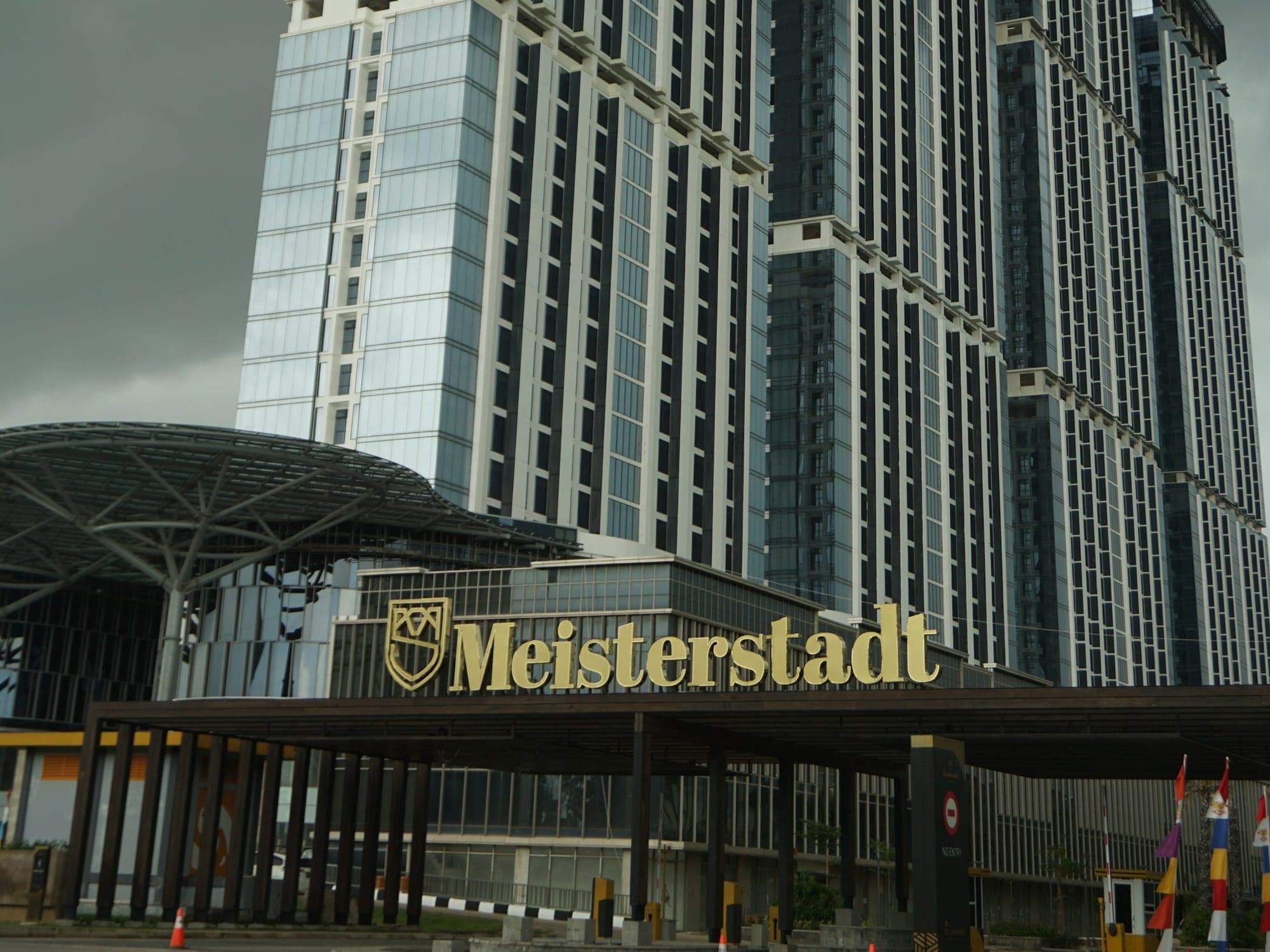 The Meisterstadt Pollux Habibie towers and their entrance canopy in Batam Centre under an overcast sky
