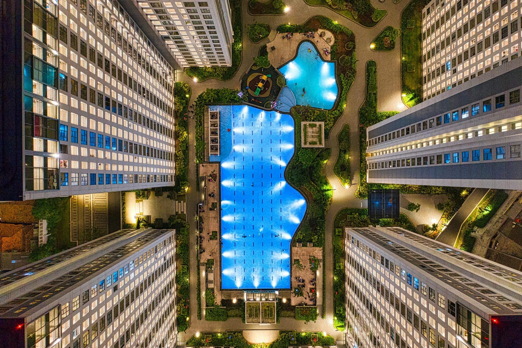 Night aerial view of modern hotel buildings surrounding an illuminated swimming pool in Indonesia