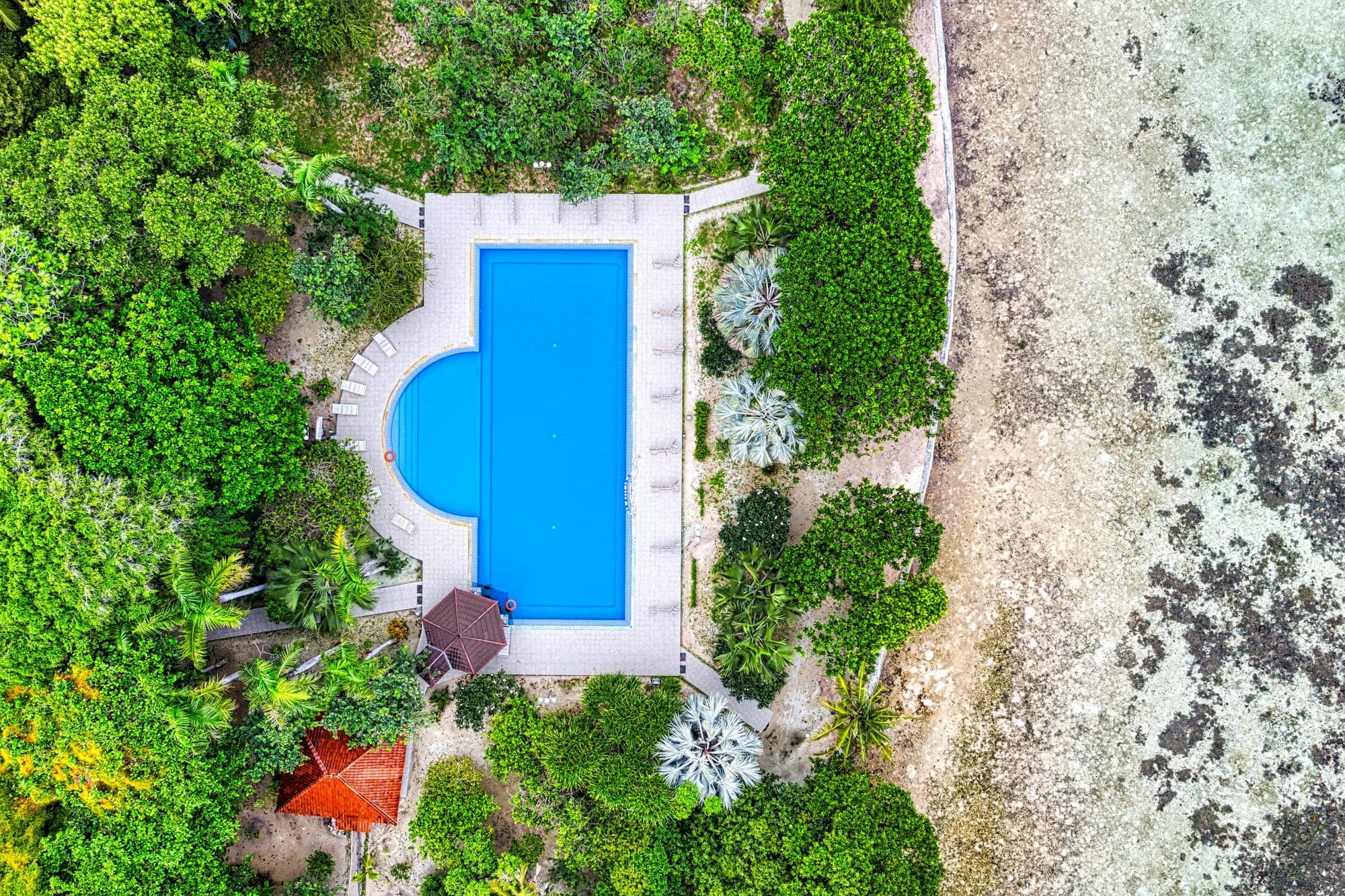 Aerial drone view of a tropical resort swimming pool directly at the Indonesian coastline