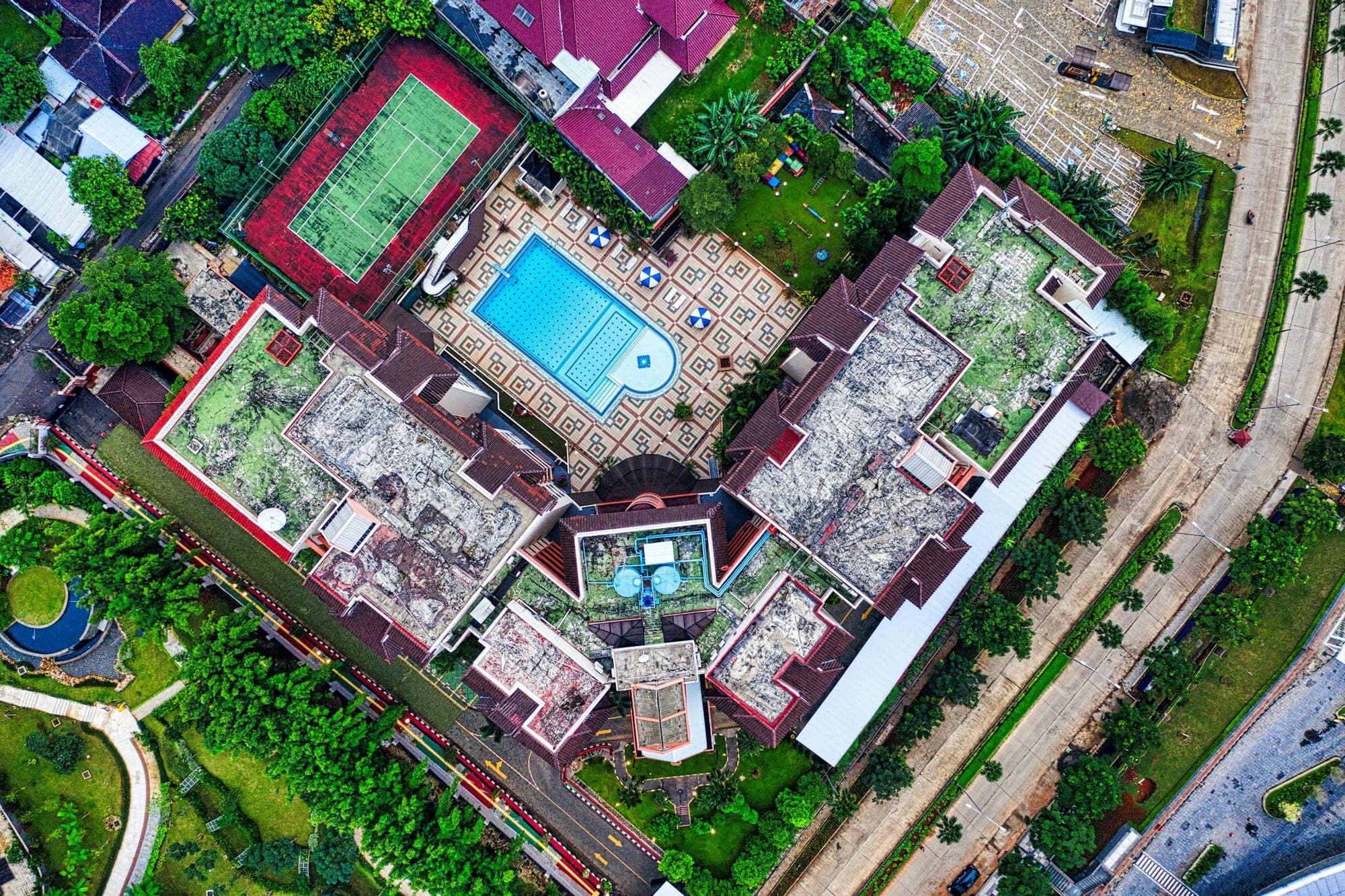 Top-down aerial view of a hotel swimming pool surrounded by modern urban buildings in Indonesia