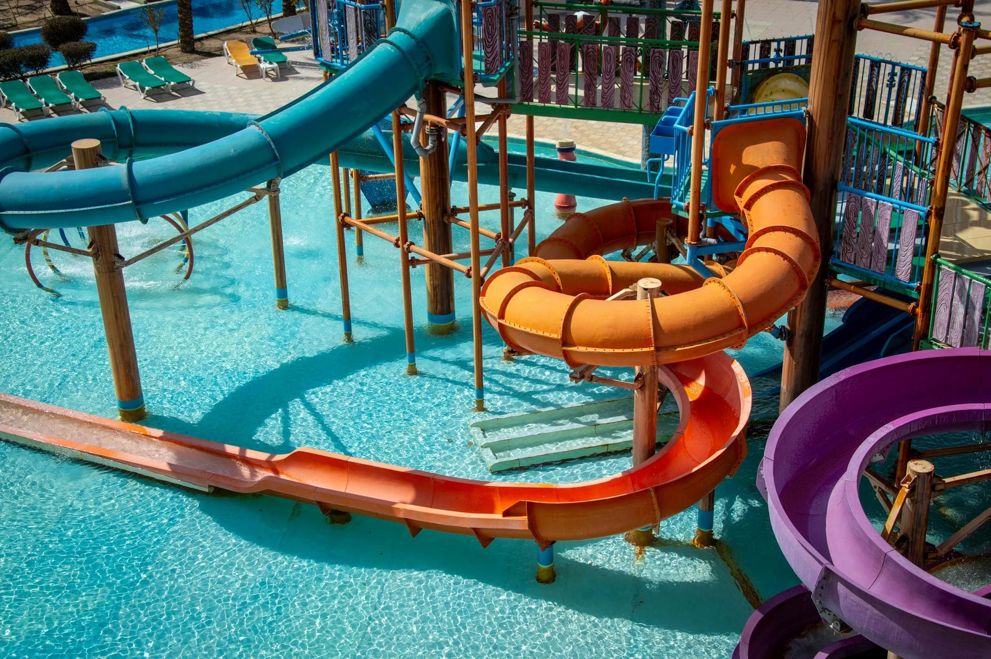 Colorful outdoor water park slides in orange and purple under a bright sunny sky
