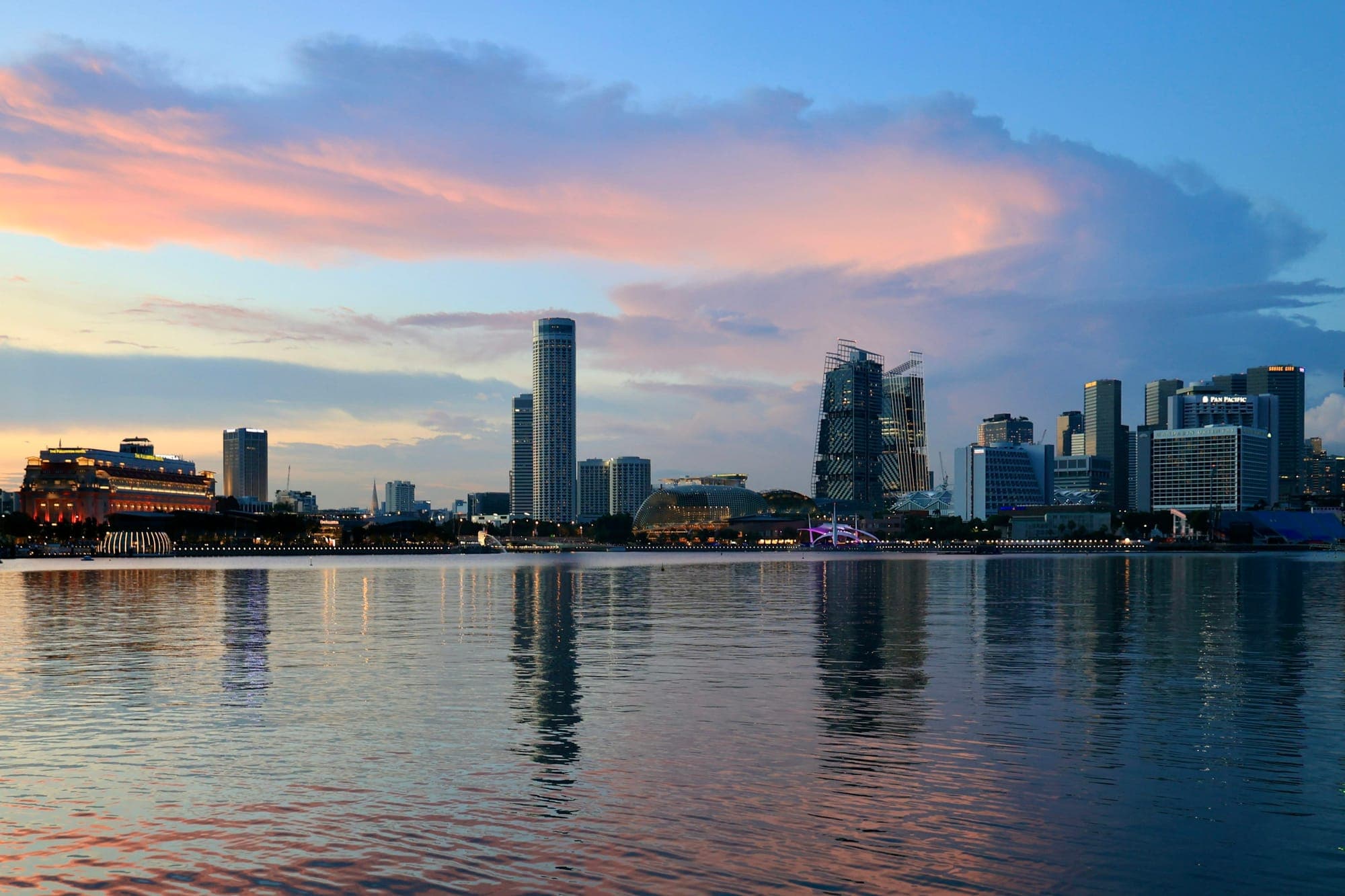 Singapore downtown skyline reflected in Marina Bay waters at dusk, viewed from the waterfront