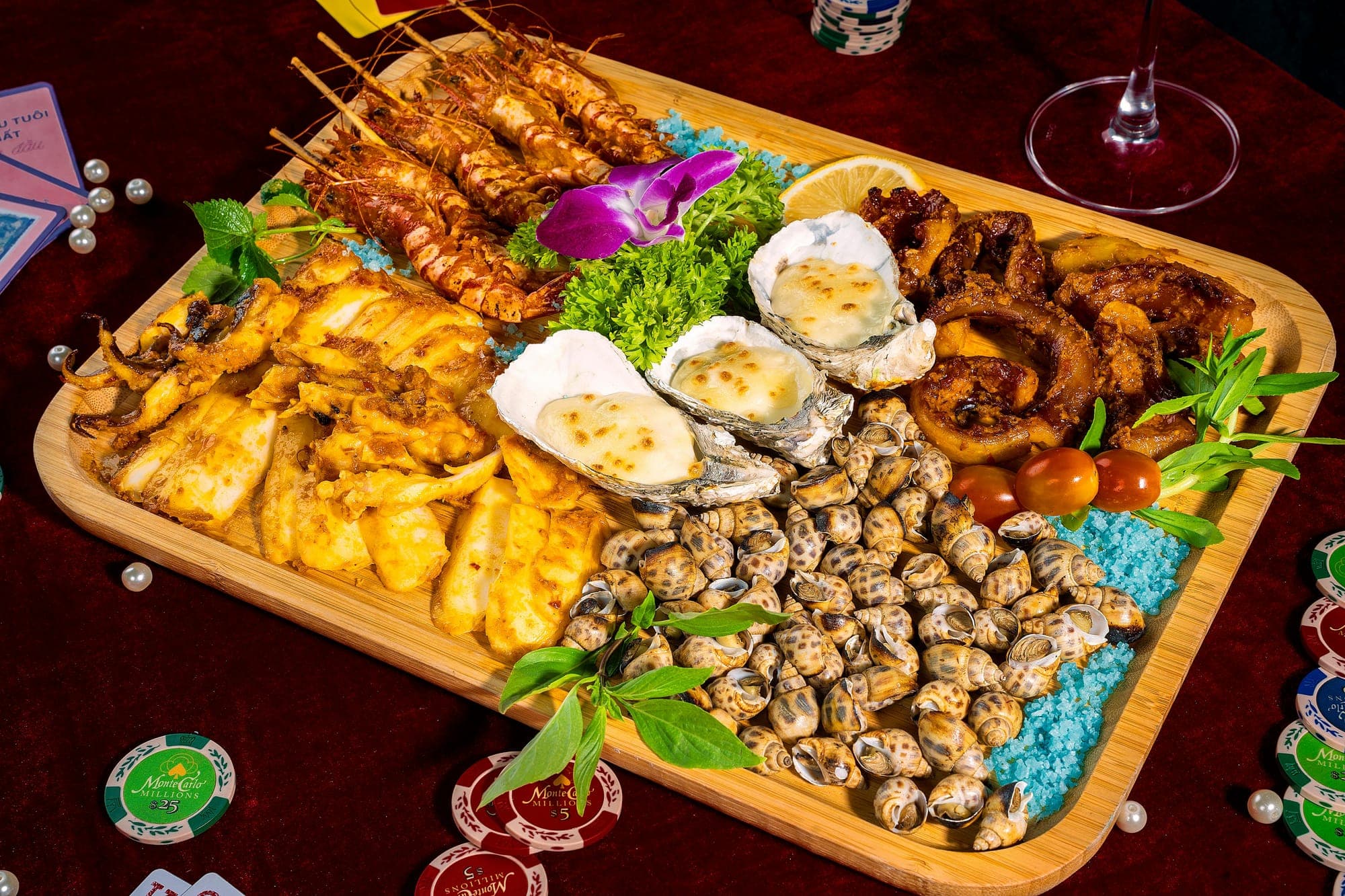 Fresh seafood platter with clams, shrimp and oysters arranged on a wooden board with herbs and lemon